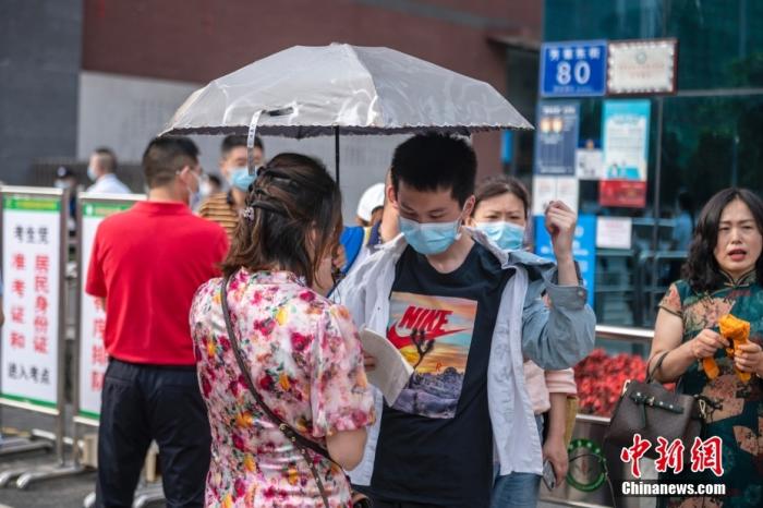 成都玉林中学考点外，一位母亲打着伞与即将进入考场的孩子交流