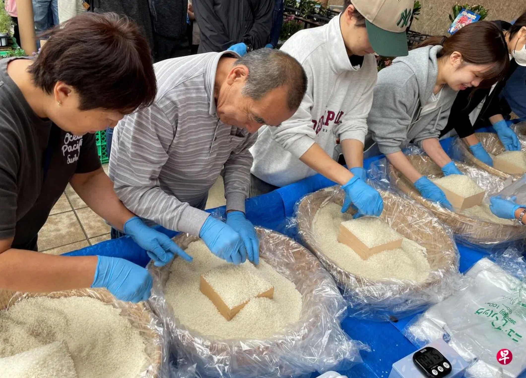 日本东京一个农贸市场近期大搞促销活动，让顾客用小木盒装尽可能多的米来买平价米 ...